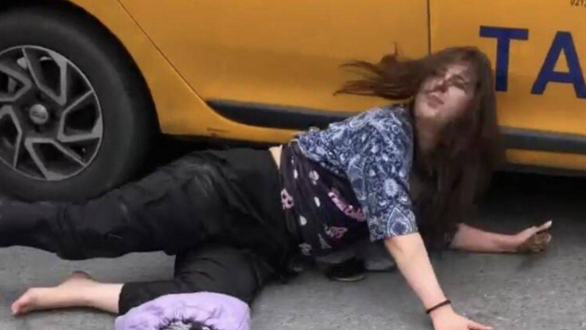 Taksinin altına girerek tepki gösterdi